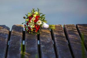 buquê de flores de rosas vermelhas e brancas na ponte de madeira com sol da tarde foto