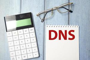 sistema de nomes de domínio dns está escrito em um bloco de notas branco perto de uma calculadora foto