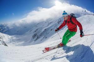 esquiador esqui downhill nas montanhas altas contra o pôr do sol foto