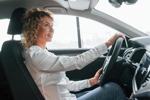 fazendo test-drive. mulher com cabelo loiro encaracolado está no autosalon foto