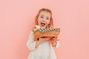 menina feliz de pé contra um fundo rosa e comemorando a páscoa foto