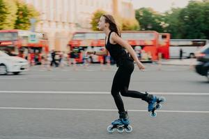 atividades ao ar livre para ser saudável e em forma. mulher europeia em boa forma física passeios de patins em patins em linha vestidos com roupa ativa tem descanso ativo. conceito de estilo de vida esportivo foto