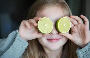 criança linda garota cobrindo os olhos com limão foto