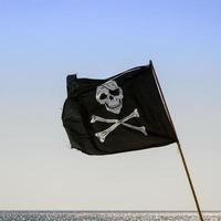 bandeira de pirata, acenando com fundo azul do mar foto