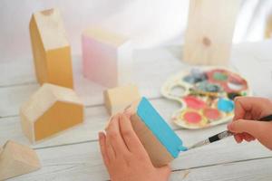 mãos de menina adolescente pintando casa de brinquedo de madeira em azul. hobby ou lazer durante a quarentena. foto