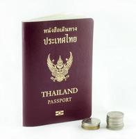 passaporte tailandês e moedas tailandesas em fundo branco
