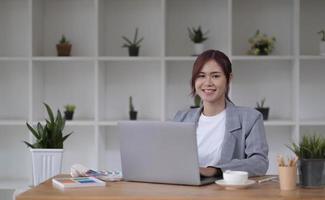 bela sorridente jovem designer gráfico sentado na mesa no escritório e trabalhando foto