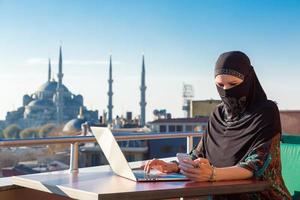 mulher muçulmana tradicionalmente vestida, trabalhando no computador foto
