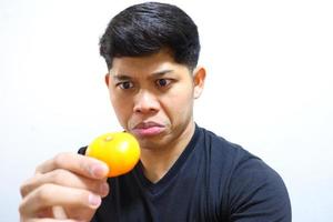 homem asiático atraente comendo laranjas. isolado no fundo branco foto