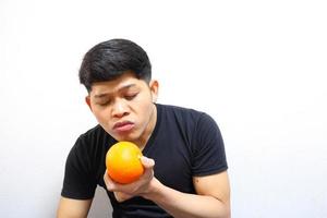 homem asiático atraente comendo laranjas. isolado no fundo branco foto