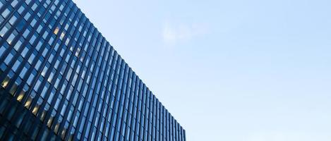 arranha-céus moderno contra o céu azul. vista inferior de um arranha-céu no distrito comercial. vista de baixo ângulo da fachada de vidro de um prédio de escritórios. banner com espaço de cópia. foto