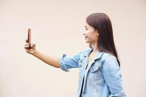 mulher asiática alegremente tira uma selfie com o telefone dela. foto