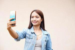 mulher asiática alegremente tira uma selfie com o telefone dela. foto