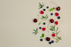cereja fresca, mirtilo, framboesa, hortelã e folha de alecrim na vista superior com fundo de cor bege para o conceito de comida saudável. foto