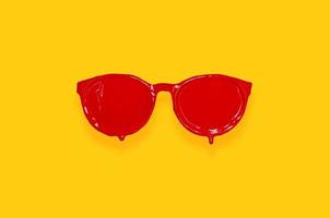 cor de cartaz vermelho pintado em óculos de sol com fundo amarelo. foto