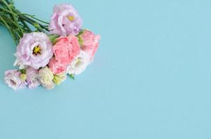 lindo cravo rosa e amarelo e flores roxas de eustoma ou lisianthus sobre fundo azul pastel. foto