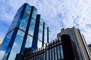 céu azul e nuvens refletidas no vidro de prédios comerciais no centro da cidade em um dia ensolarado. foto