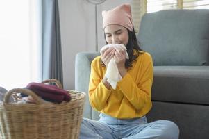 jovem mulher feliz vestindo camisa amarela dobrando roupas na sala de estar, conceito de lavanderia foto