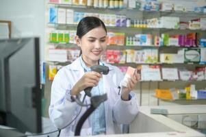 farmacêutico feminino escaneando código de barras em uma caixa de remédios em uma farmácia moderna. foto