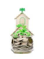 moedas em garrafa de vidro e casa e árvore em fundo branco, economia de negócios e investimento ou conceito de crescimento econômico de sorte foto