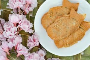 bolos taiyaki em prato branco com flor de cerejeira, confeitaria japonesa foto