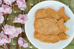 bolos taiyaki em prato branco com flor de cerejeira, confeitaria japonesa foto