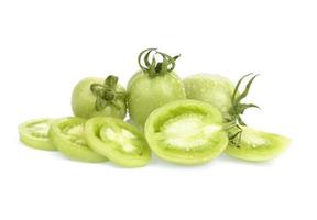 tomates verdes frescos, inteiros e fatiados, têm um spray de água de superfície sobre fundo branco. foto