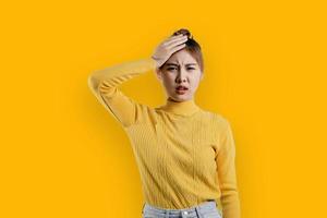 retrato de uma linda mulher asiática em uma camisa amarela em pé com um rosto tenso. conceito de retrato usado para propaganda e sinalização, isolado sobre o fundo em branco, copie o espaço. foto
