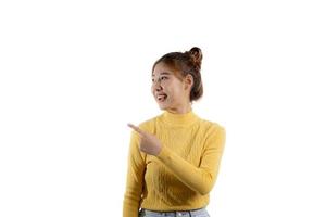retrato de uma linda mulher asiática em uma camisa amarela em pé e apontando. conceito de retrato usado para propaganda e sinalização, isolado sobre o fundo em branco, copie o espaço. foto