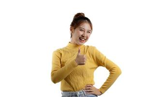 retrato linda mulher asiática em uma camisa amarela em pé, levantando a mão e mostrando o polegar. conceito de retrato usado para propaganda e sinalização, isolado sobre o fundo em branco, copie o espaço. foto