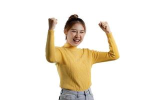 retrato de uma linda mulher asiática em uma camisa amarela em pé com as mãos para cima de alegria. conceito de retrato usado para propaganda e sinalização, isolado sobre o fundo em branco, copie o espaço. foto