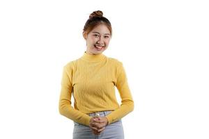 um retrato de uma linda mulher asiática em uma camisa amarela em pé sorrindo alegremente. conceito de retrato usado para propaganda e sinalização, isolado sobre o fundo em branco, copie o espaço. foto
