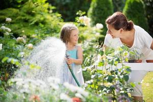 menina e vovó regando flores no jardim foto