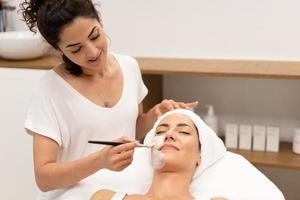 esteticista aplicando máscara facial no cliente foto