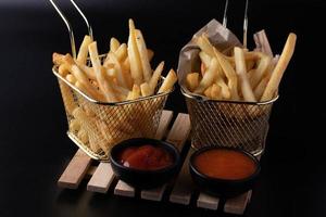 batatas fritas em uma cesta em um fundo preto foto