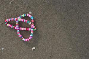 pulseira de arco-íris no conceito de background.lgbt de areia. espaço de cópia foto