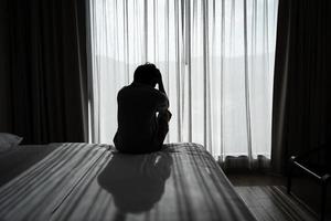 jovem solitário se sentindo deprimido e estressado sentado no quarto escuro, emoção negativa e conceito de saúde mental foto