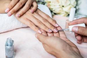 belas unhas de manicure pintar com glitter e verniz no salão de beleza foto