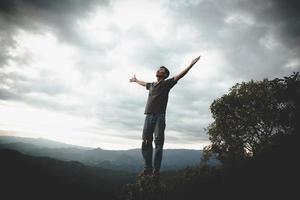 homem rezando nas montanhas levantou as mãos viajar estilo de vida espiritual relaxamento conceito emocional, liberdade e aventura de viagem. foto