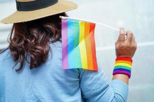 senhora asiática segurando a bandeira da cor do arco-íris, símbolo do mês do orgulho LGBT, comemorar anual em junho social dos direitos humanos de gays, lésbicas, bissexuais, transgêneros. foto