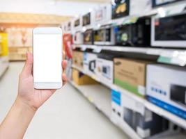 mão segure o celular com loja eletrônica no supermercado foto