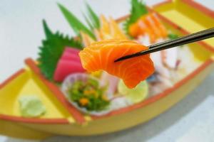 salmão em pauzinhos com sashimi japonês definido na placa do barco foto