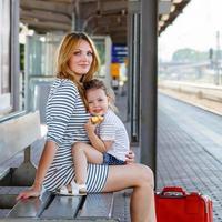 menina bonitinha e mãe em uma estação de trem.