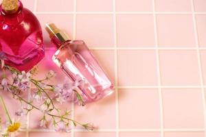 frasco cosmético de perfume rosa e flores naturais foto