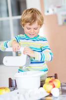 garoto garoto loiro engraçado fazer bolo de maçã dentro de casa foto