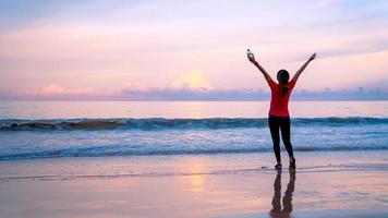 garota correndo treino corrida na praia pela manhã. relaxe e feliz correndo no mar. no verão foto