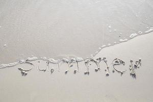 palavra verão escrita à mão na areia. feche a textura de areia na praia no verão. férias, conceito de férias, foto