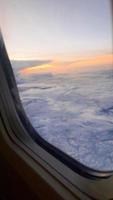 vista da janela do avião. o céu com nuvens brancas e fundo azul. tempo claro com uma luz de sol afundando e revelando as asas da aeronave foto