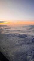 vista da janela do avião. o céu com nuvens brancas e fundo azul. tempo claro com uma luz de sol afundando foto