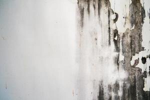 textura áspera na parede cinza forma áspera devido à camada de tinta descascada devido à chuva. foto